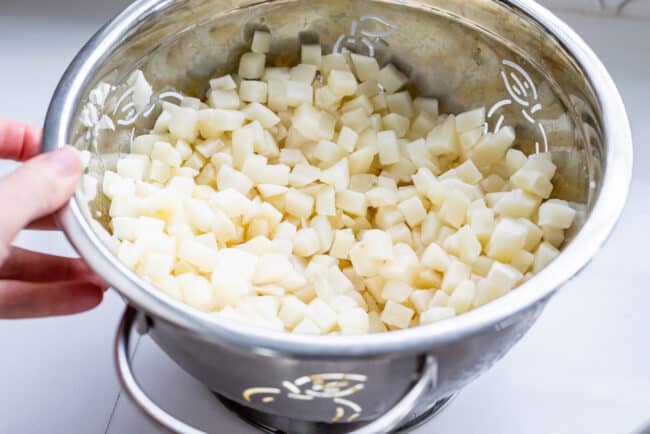 frozen hash brown potatoes thawing in a metal colander. 