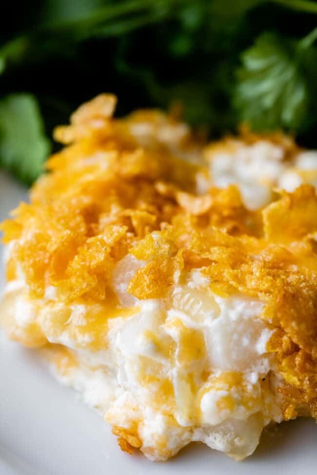 close up shot of cheesy hashbrown potatoes on a plate with parsley.