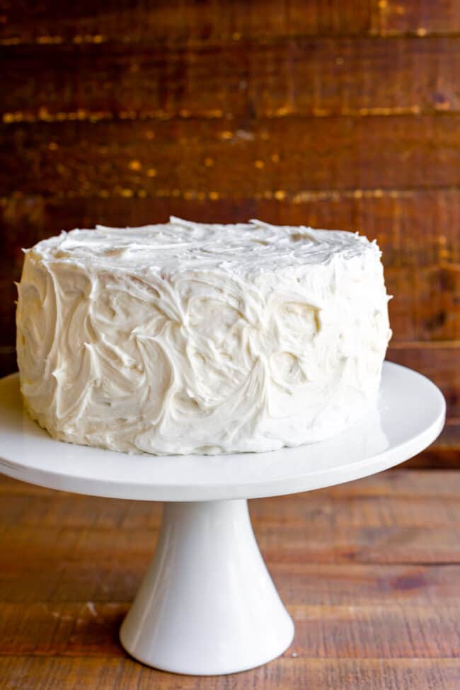 white cake with vanilla frosting on a cake stand.