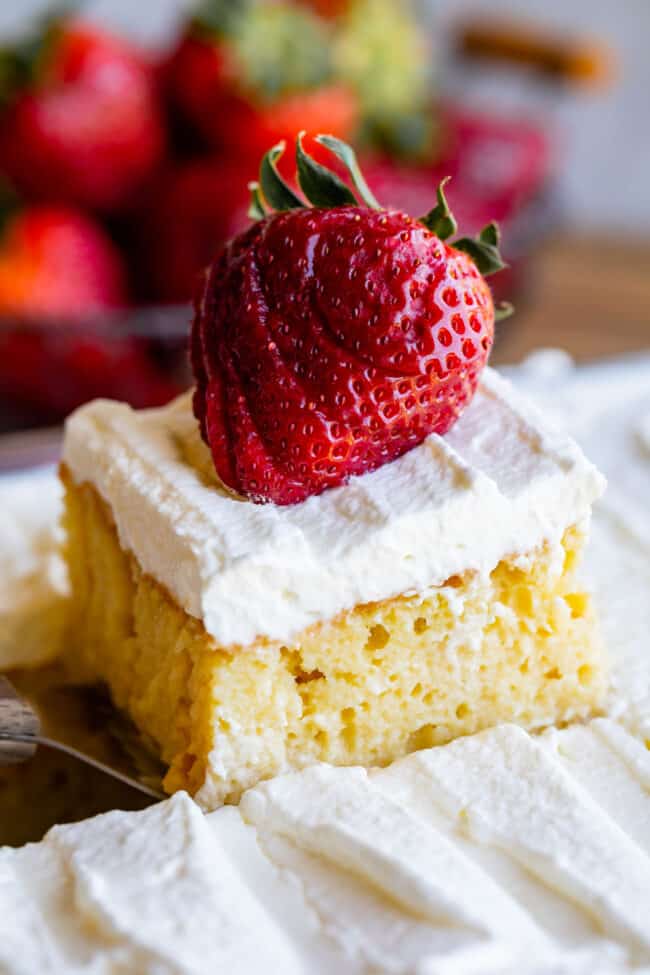 a piece of tres leches cake with a sliced strawberry on top.