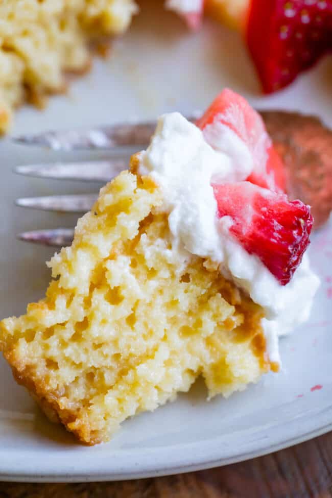 a bite of tres leches cake with strawberries on top.