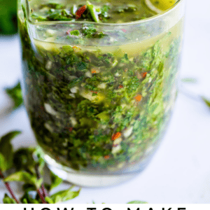 A glass filled with vibrant green chimichurri sauce and a spoon, fresh herbs visible throughout. Text below reads: Chimichurri Sauce. The Food Charlatan.