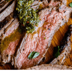 sliced flank steak with chimichurri sauce.