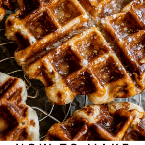 Close-up of golden-brown Liege waffles sprinkled with coarse sugar, cooling on a wire rack. Text below reads: “Liege Waffles, The Food Charlatan.”.