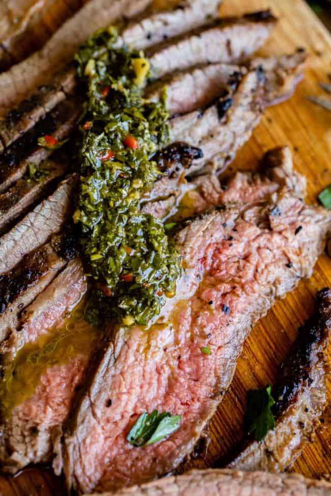 sliced grilled flank steak with chimichurri sauce.