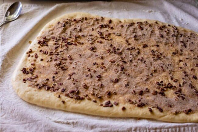 how to make pecan rolls showing the Brioche dough spread with caramel sauce and pecans