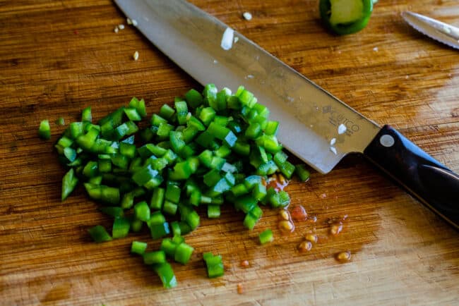 finely chopped jalapenos for pico de gallo on a wooden cutting board.
