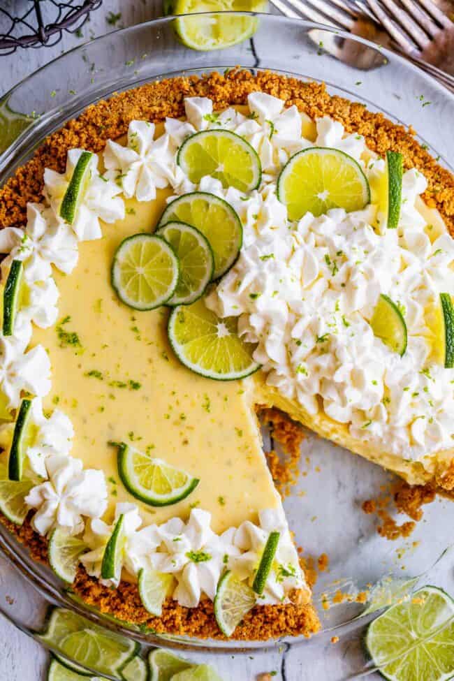 key lime pie with graham cracker crust, whipped cream, and lime slices.
