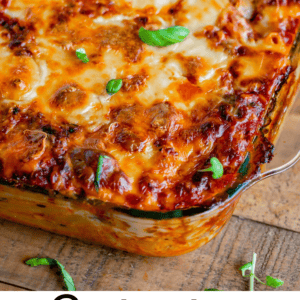 A baked ziti casserole with melted cheese and a golden top, garnished with fresh basil in a glass dish. Text reads: “Postpartum Ziti – A comforting meal to bring to new moms. The Food Charlatan.”.