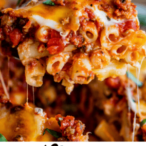 A close-up of cheesy baked ziti with melted cheese and savory meat sauce, being lifted from a dish. Text below reads “Cheesy Baked Ziti: A comforting meal to bring to new moms. The Food Charlatan.”.