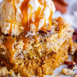 slice of pumpkin dump cake with ice cream and caramel sauce on top