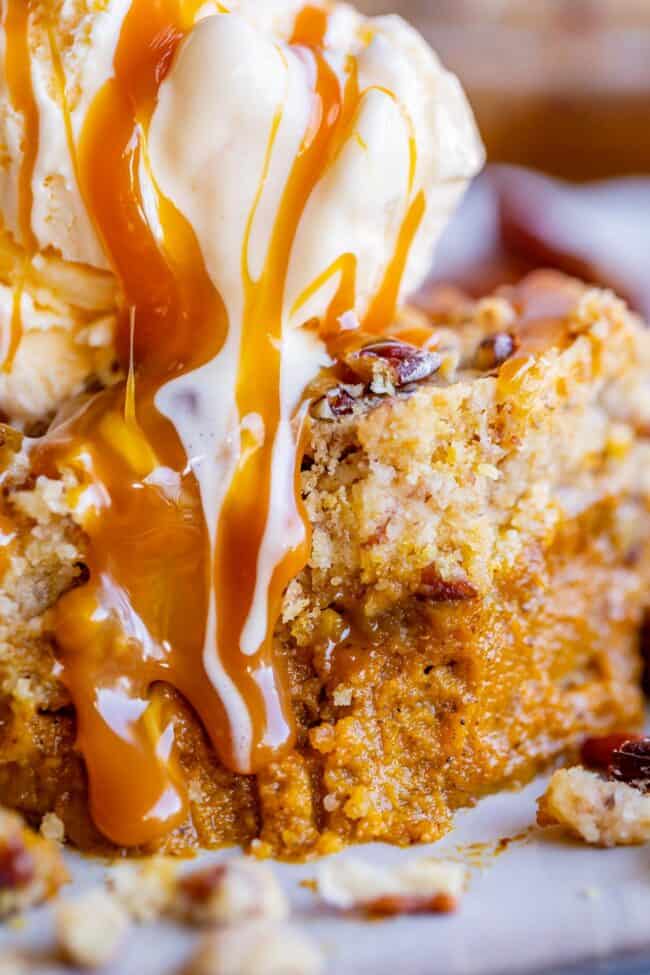 slice of pumpkin pie cake with yellow cake mix topped with ice cream and drizzled with caramel sauce
