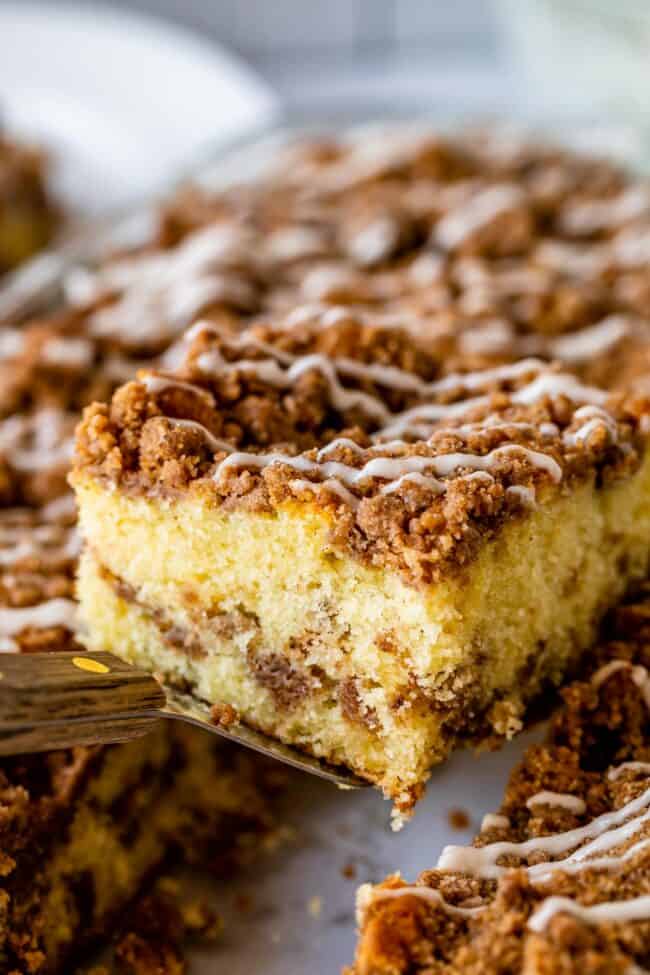 Streusel topped coffee cake slice being lifted on a spatula from pan.