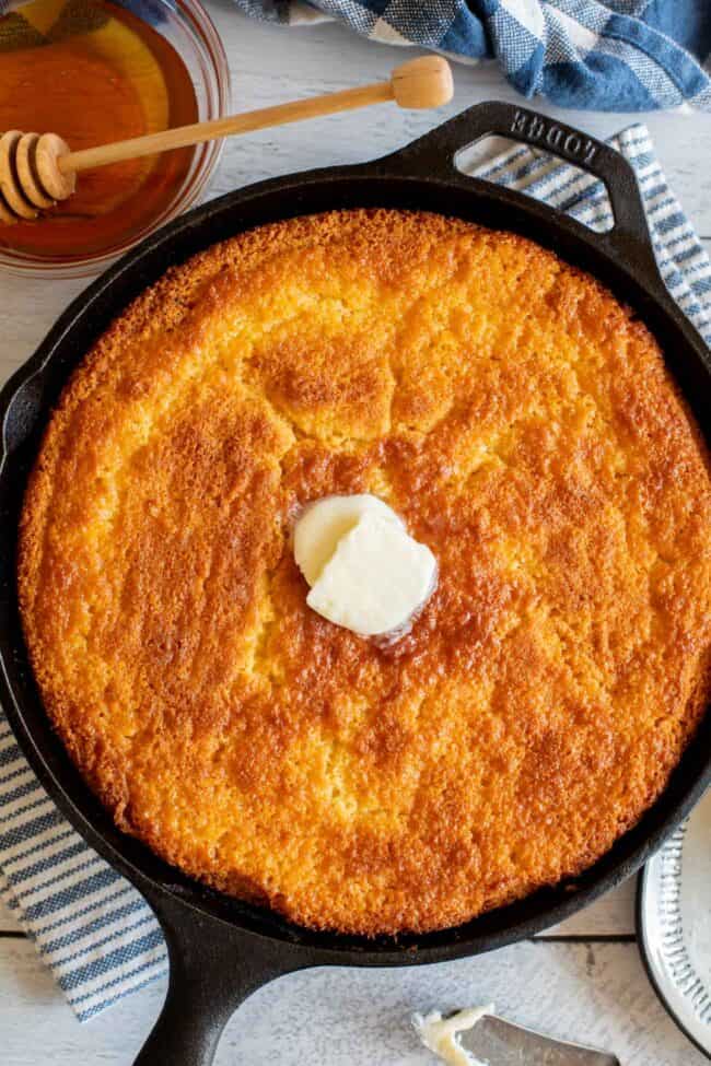 overhead shot of cornbread in a cast iron skillet with a pat of butter on top