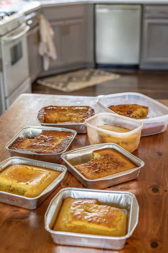 7 different batches of cornbread in different trays and pans, laid out on a table