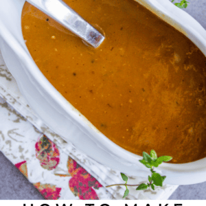 homemade turkey gravy in a white gravy boat with a ladle in it.