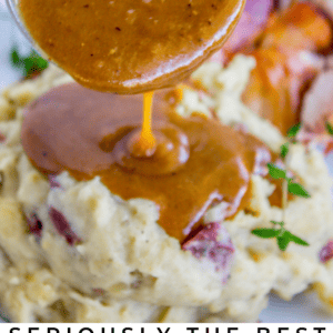 A spoon pours rich, brown turkey gravy over mashed potatoes, with carrots and herbs on the side. Text reads: Seriously the Ultimate Make Ahead Turkey Gravy. Perfect for the Holidays. The Food Charlatan.