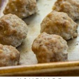 baked meatballs lined up on a baking sheet.