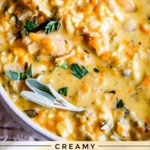 A bowl of creamy turkey rice soup, garnished with fresh herbs, featuring tender turkey, wild rice, carrots, and celery. Text on the image reads: Creamy Turkey Wild Rice Soup Crockpot/Stovetop.
