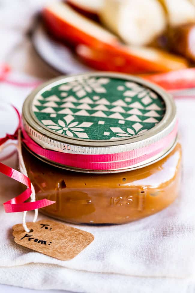 a jar of dulce de leche with a Christmas wrapping paper lid and a gift tag.