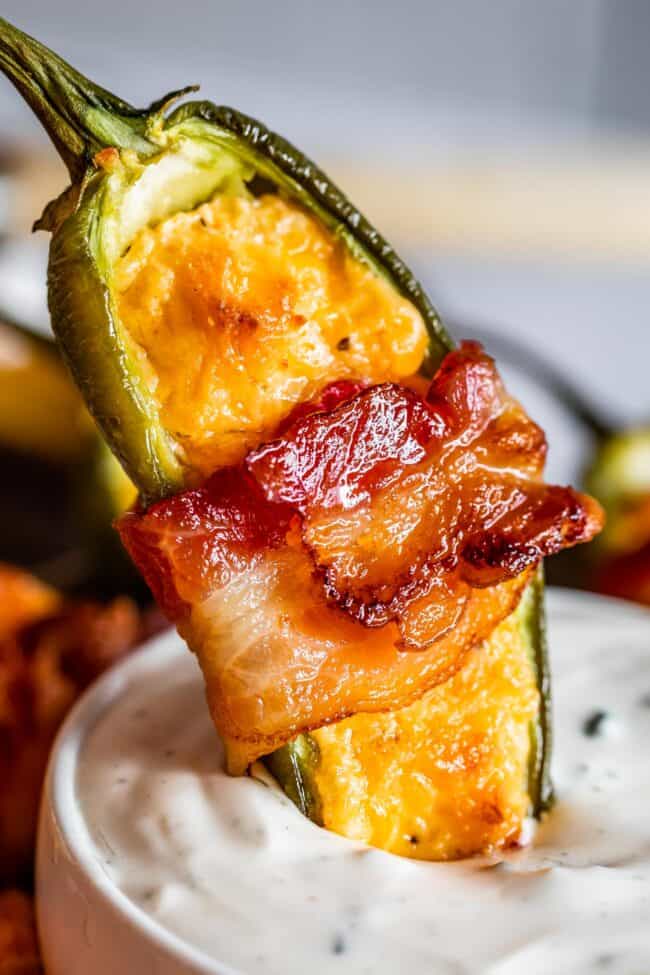 bacon wrapped jalapeno popper being dipped in ranch.