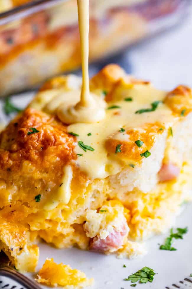 cheesy ham and egg casserole with biscuits and hollandaise sauce drizzled on top.