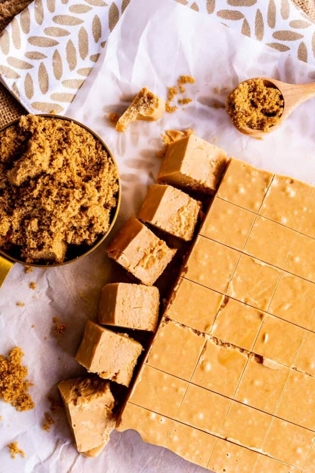 penuche fudge cut into neat squares with brown sugar in a measuring cup.