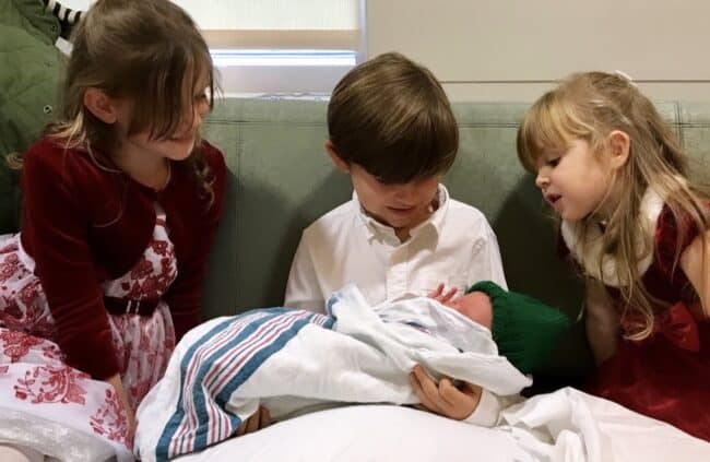 Older siblings looking at baby in hospital