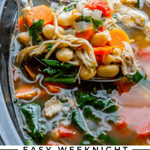 A close-up of chicken and white bean soup with kale, carrots, and parmesan shavings simmering in a slow cooker. Text overlay reads: Easy Weeknight Chicken and White Bean Soup with Kale & Parmesan Shavings.