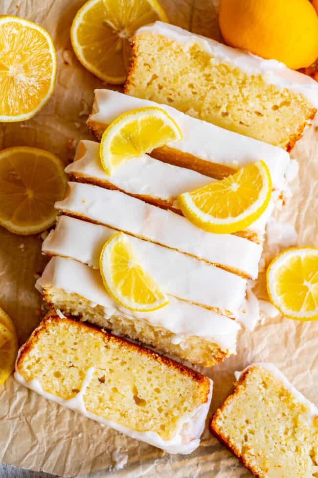 sliced lemon loaf with glaze and fresh lemon slices.