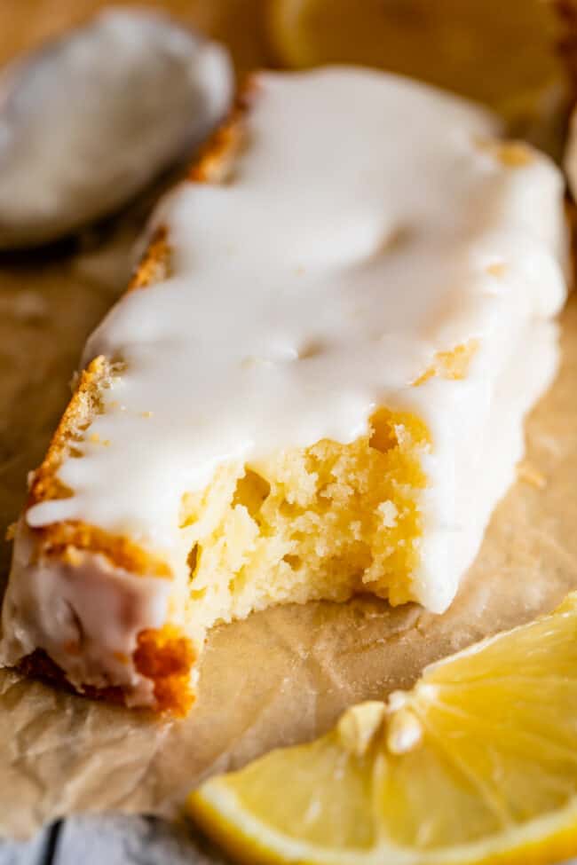 a slice of lemon loaf with glaze and a bite taken out of it.