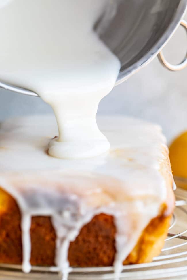 pouring glaze onto a loaf of lemon quick bread.