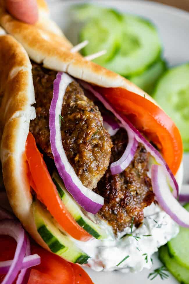 Greek gyro with meat, tzatziki sauce, tomatoes, cucumber, red onion, and fresh dill in a pita. 