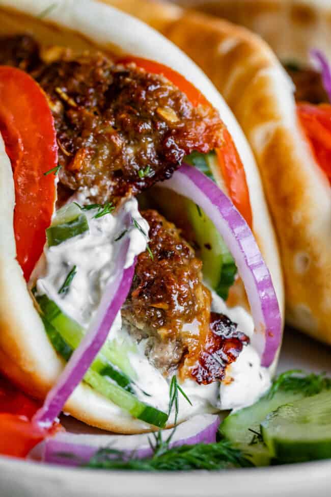 Greek gyro with meat, tzatziki sauce, tomato, cucumber, fresh dill, and red onions in a pita. 