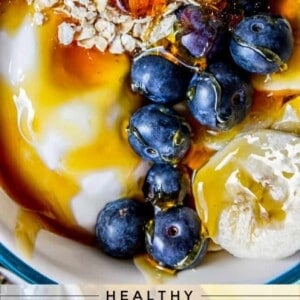 A bowl of overnight oats topped with blueberries, banana slices, honey, yogurt, and a sprinkle of oats. Text below reads: Healthy Banana Blueberry Overnight Oats.
