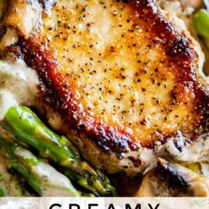 A close-up of a golden-brown pan-seared pork chop in sauce, topped with creamy sauce and served with sautéed asparagus and mushrooms. Text overlay reads: Creamy Pan Seared Pork Chops with Asparagus.