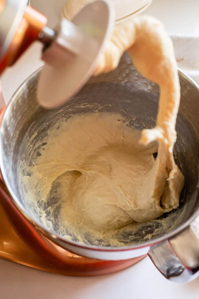 lifting a dough hook from sticky bread dough in a stand mixer. 