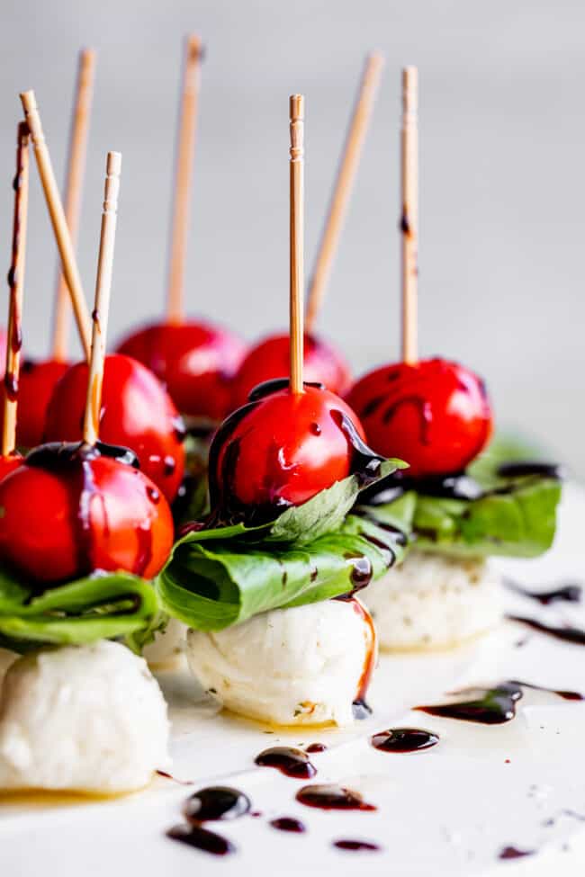 caprese bites appetizer with mozzarella balls, fresh basil, cherry tomatoes, and balsamic reduction. 