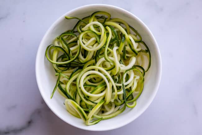 zoodles in a white bowl on a countertop shot from overhead