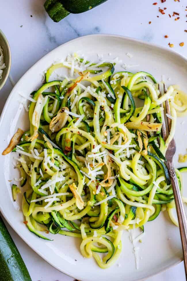 zucchini noodles on a plate with cheese and a fork.