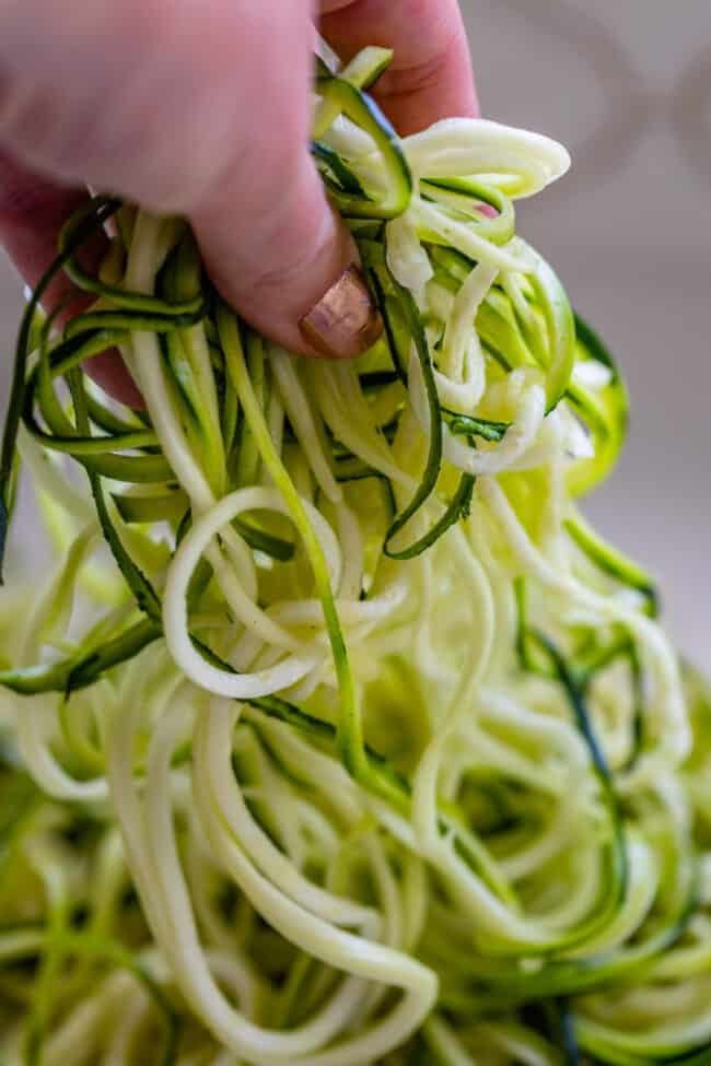 hand lifting zoodles off of counter top.