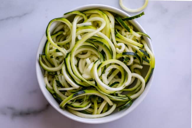 curly zoodles in a white bowl on a counter