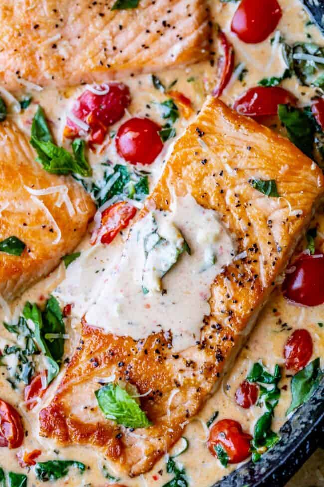 creamy tuscan salmon with cherry tomatoes, spinach, and fresh basil.
