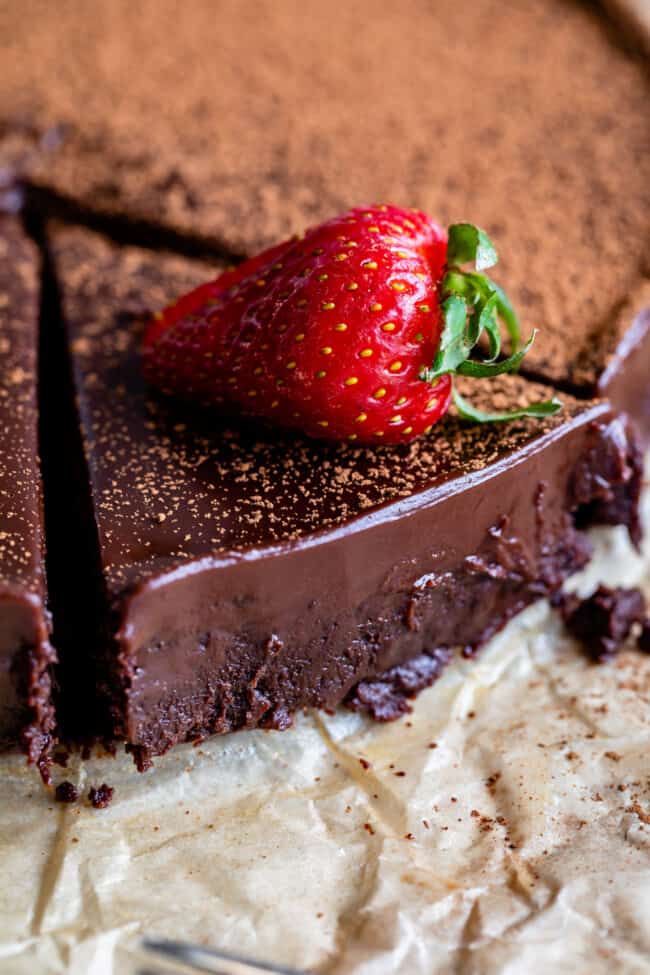 a slice of flourless chocolate cake cut from the cake with a strawberry on top.
