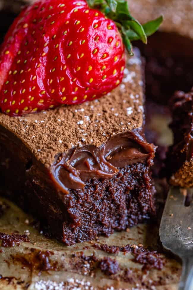 flourless chocolate cake with a forkful removed and a strawberry on top.