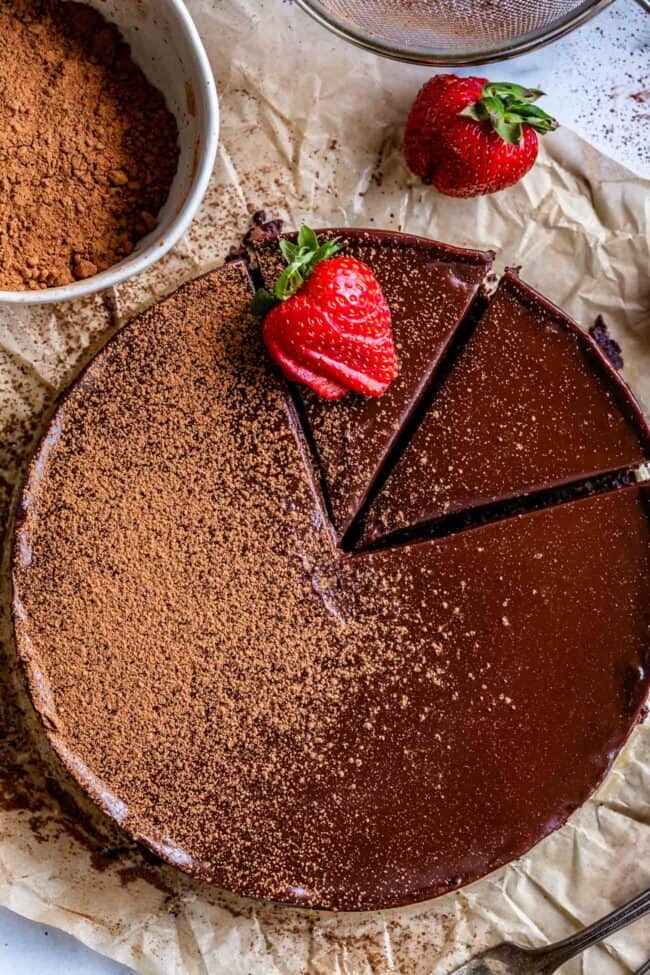 flourless chocolate cake dusted with cocoa powder with strawberries.