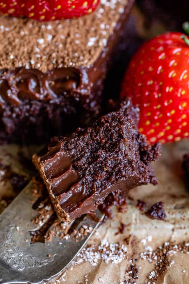 flourless chocolate cake with a forkful removed and fresh strawberries.
