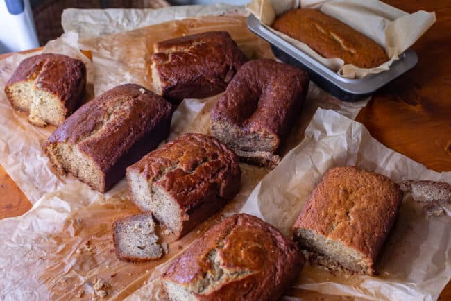 8 loaves of banana bread with slices cut off, some sunken, some cracked.