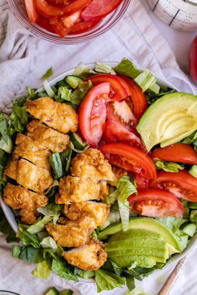 Crispy chicken salad in a bowl with tomato and avocado