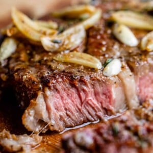close up of ribeye steak, medium rare, with garlic cloves on top